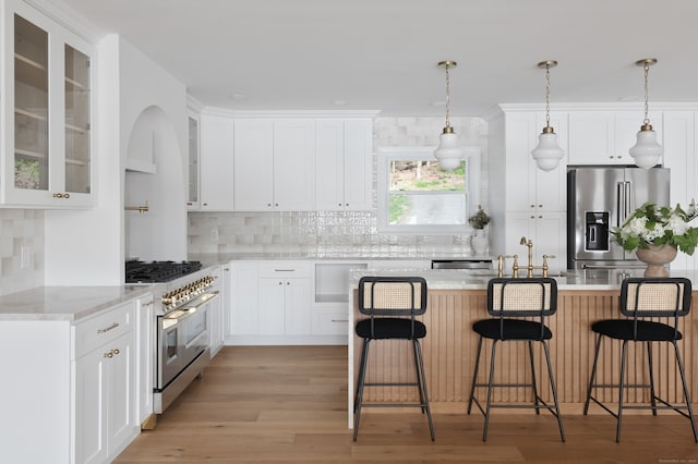 kitchen featuring tasteful backsplash, light wood finished floors, a kitchen bar, and high quality appliances