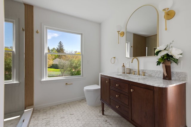 bathroom with toilet, baseboards, a wealth of natural light, and vanity