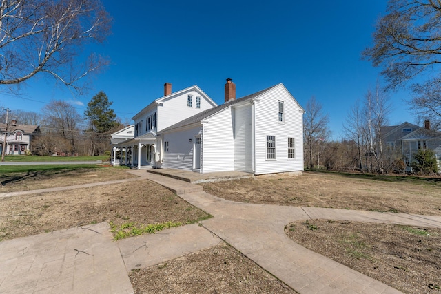 rear view of property with a porch and a chimney