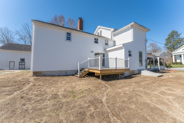 rear view of property with a chimney and a deck