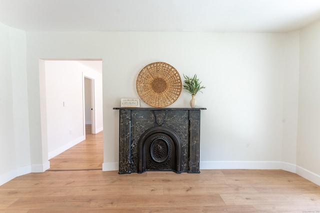 living area with baseboards, a fireplace with flush hearth, and wood finished floors