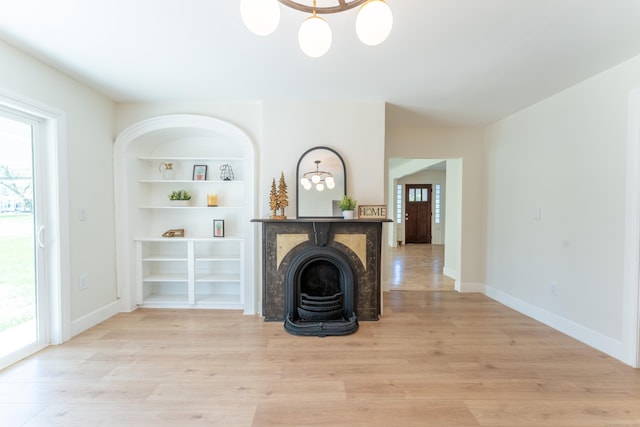 unfurnished living room featuring a healthy amount of sunlight, light wood finished floors, and built in shelves
