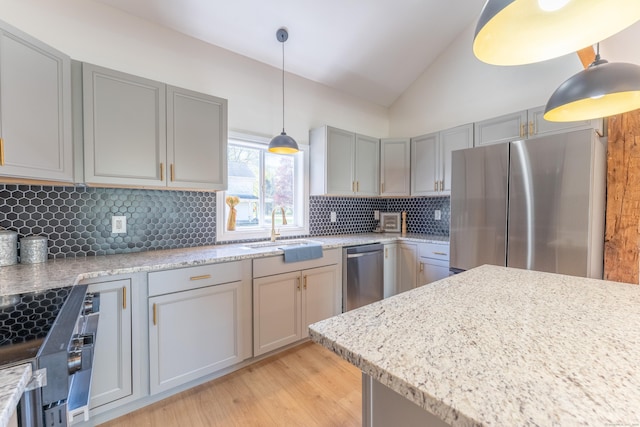 kitchen with lofted ceiling, tasteful backsplash, a sink, gray cabinetry, and stainless steel appliances