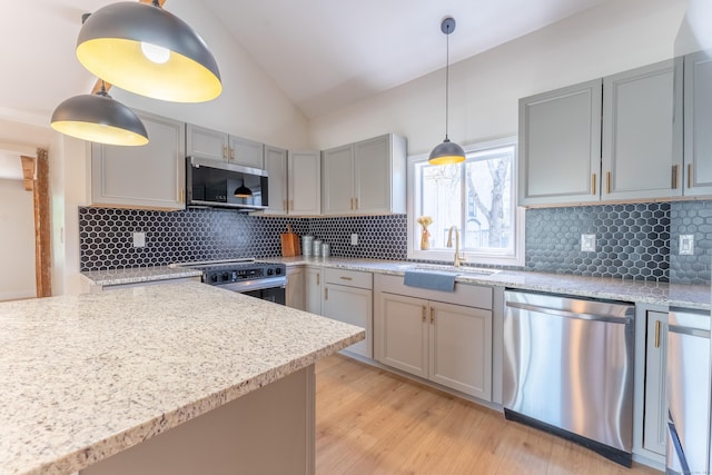kitchen featuring lofted ceiling, gray cabinets, tasteful backsplash, a sink, and stainless steel appliances