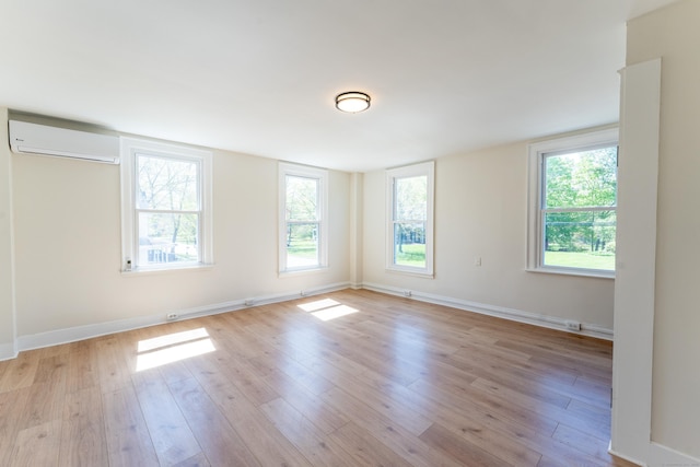 empty room featuring baseboards, light wood-style flooring, and a wall mounted AC