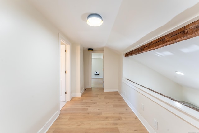 hallway with baseboards, light wood-type flooring, and lofted ceiling