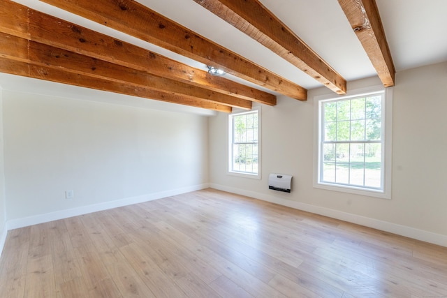unfurnished room featuring heating unit, baseboards, beamed ceiling, and light wood-style floors
