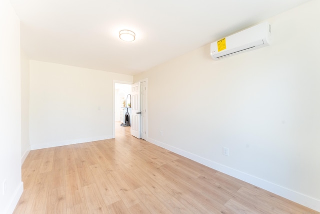 spare room featuring baseboards, light wood-style flooring, and a wall mounted AC