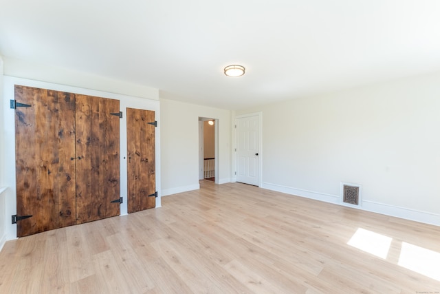 unfurnished room with visible vents, light wood-style flooring, and baseboards