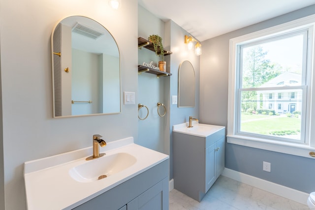full bathroom featuring visible vents, marble finish floor, baseboards, two vanities, and a sink