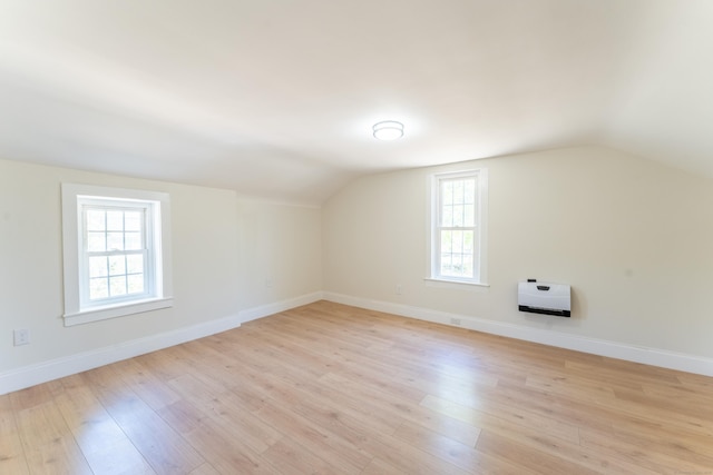 additional living space featuring baseboards, vaulted ceiling, and light wood-type flooring