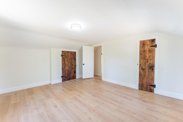interior space with baseboards, light wood finished floors, and lofted ceiling