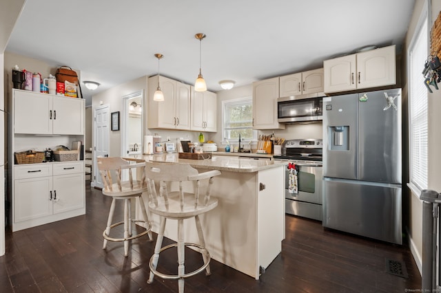 kitchen with light stone countertops, a breakfast bar, dark wood-type flooring, and appliances with stainless steel finishes
