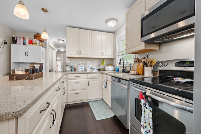 kitchen with dark wood-style floors, light stone counters, stainless steel appliances, a sink, and white cabinetry
