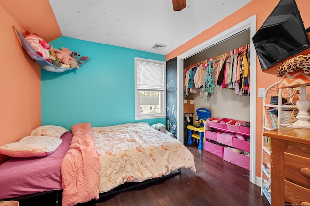bedroom with lofted ceiling, wood finished floors, visible vents, and a closet
