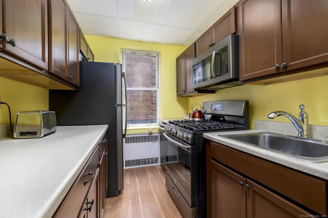 70 Strawberry Hill Ave Apt 3-2A, Stamford, CT 06902 - kitchen featuring stainless steel appliances, radiator, a sink, light wood finished floors, and a paneled ceiling