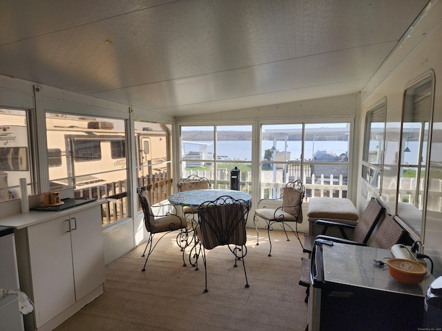 sunroom / solarium featuring carpet flooring, a water view, and lofted ceiling