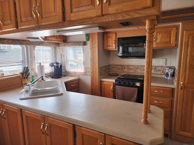 kitchen with brown cabinetry, a sink, black appliances, and light countertops