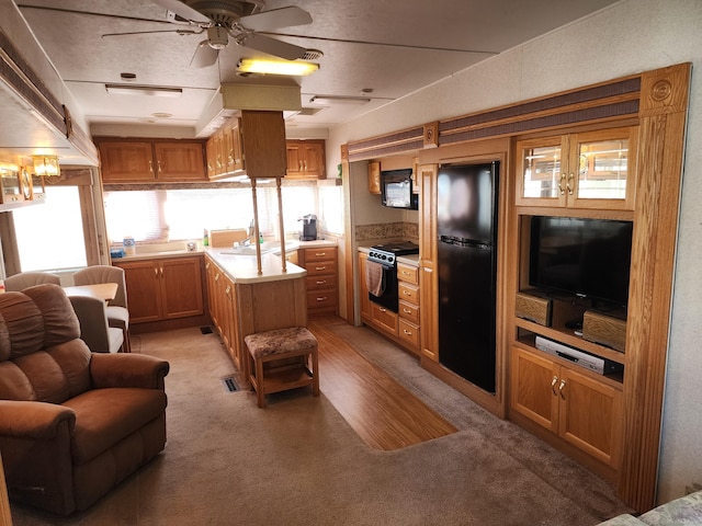 kitchen featuring freestanding refrigerator, a ceiling fan, light carpet, and light countertops