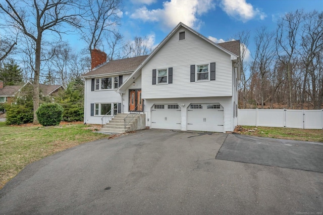 394 Woodhaven Rd, Glastonbury, CT 06033 - bi-level home featuring a chimney, a front lawn, aphalt driveway, fence, and a garage