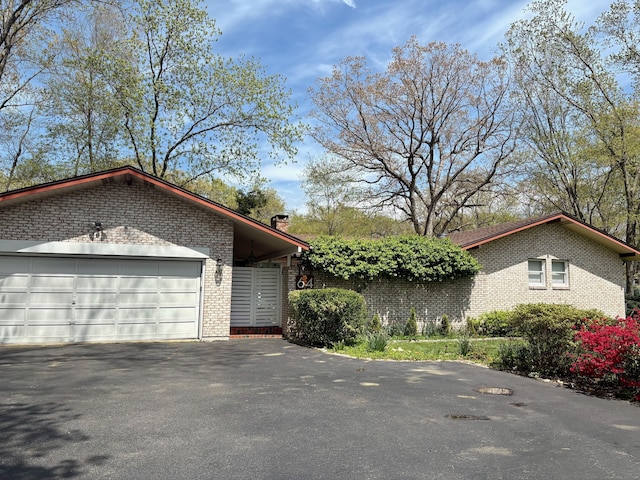 64 Sherwood Ln, Norwich, CT 06360 - view of home's exterior with aphalt driveway, an attached garage, a chimney, and brick siding