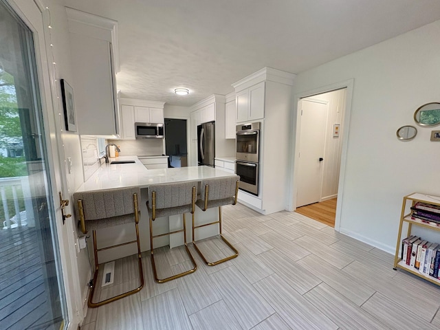 64 Sherwood Ln, Norwich, CT 06360 - kitchen with a sink, a peninsula, stainless steel appliances, a breakfast bar, and white cabinets
