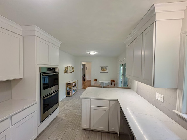 64 Sherwood Ln, Norwich, CT 06360 - kitchen featuring a peninsula, white cabinets, stainless steel double oven, and tasteful backsplash