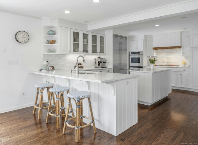 kitchen with white cabinetry, stainless steel oven, decorative backsplash, and a sink