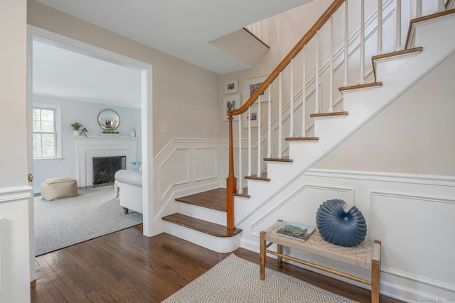 stairway featuring wainscoting, a decorative wall, and wood finished floors