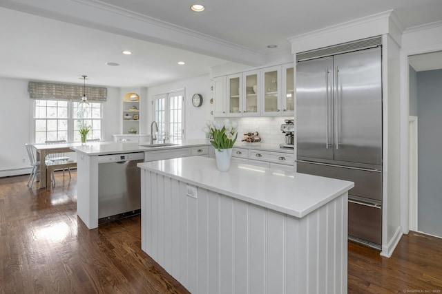 kitchen featuring glass insert cabinets, a sink, white cabinetry, a peninsula, and stainless steel appliances