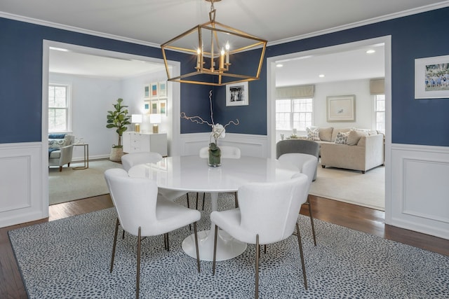 dining space with a wainscoted wall, crown molding, an inviting chandelier, and dark wood-style floors