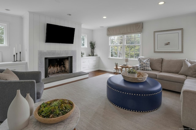 living room with a premium fireplace, recessed lighting, plenty of natural light, and wood finished floors