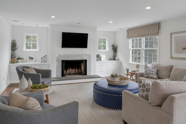 living room with crown molding, a fireplace, recessed lighting, and plenty of natural light