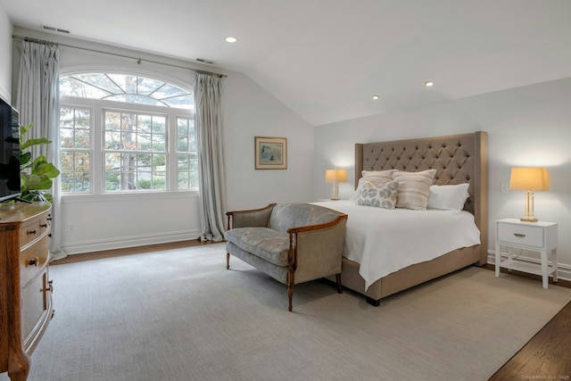 bedroom with baseboards, vaulted ceiling, visible vents, and wood finished floors