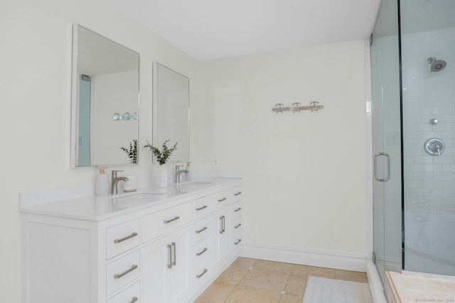 full bathroom with double vanity, baseboards, a shower stall, and a sink