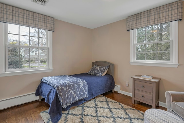 bedroom featuring a baseboard radiator, baseboard heating, baseboards, visible vents, and wood finished floors