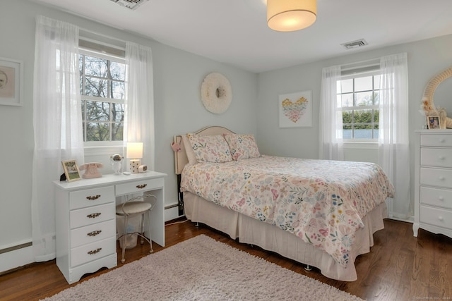 bedroom with dark wood-style flooring, baseboard heating, and visible vents