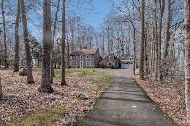 colonial-style house featuring a chimney, an attached garage, and driveway