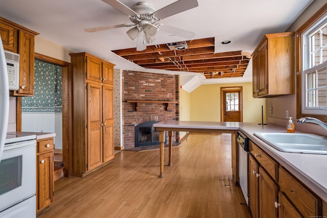 kitchen with brown cabinetry, a brick fireplace, a sink, and white appliances