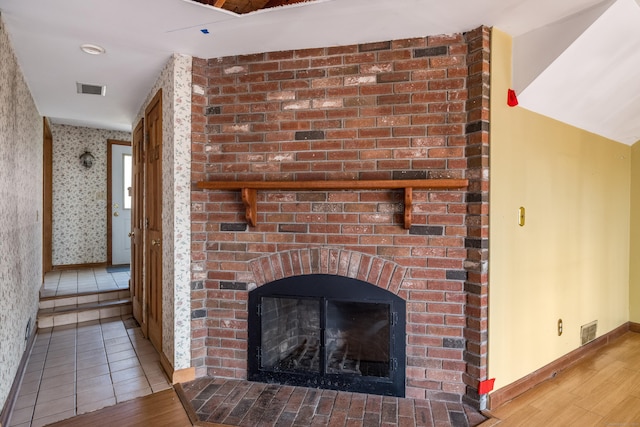 room details featuring visible vents, baseboards, wood finished floors, and a fireplace