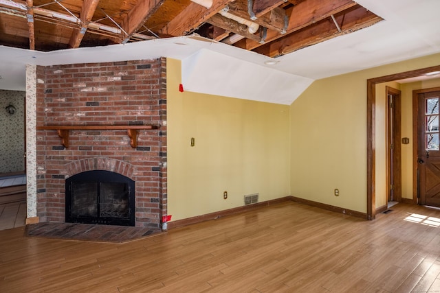 unfurnished living room featuring baseboards, wood finished floors, visible vents, and a fireplace
