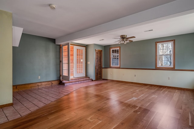 empty room featuring baseboards, a ceiling fan, wood finished floors, and visible vents
