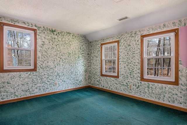 carpeted spare room with wallpapered walls, a textured ceiling, and a healthy amount of sunlight