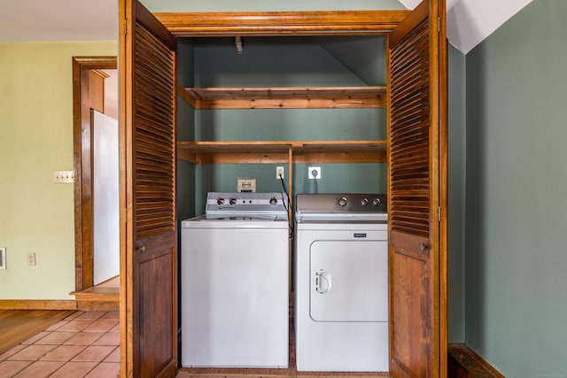 washroom with tile patterned floors, baseboards, washer and dryer, and laundry area
