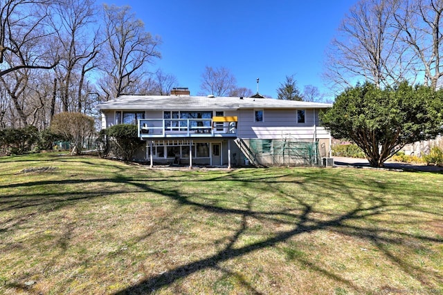 back of property with a deck, a chimney, a yard, and stairs