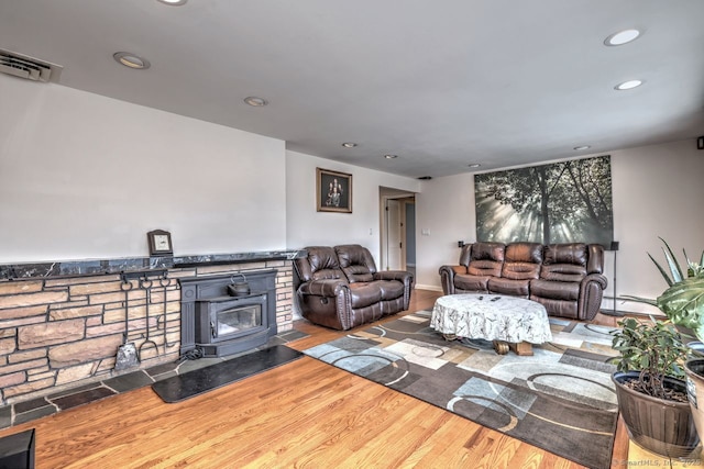 living room with recessed lighting, wood finished floors, and a wood stove