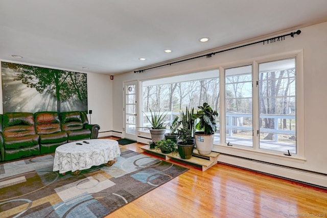 living area featuring a baseboard radiator, wood finished floors, and recessed lighting