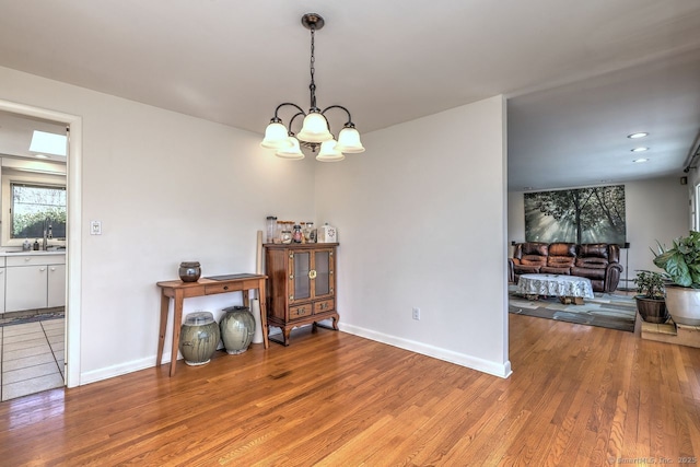 dining space with light wood finished floors, a chandelier, and baseboards