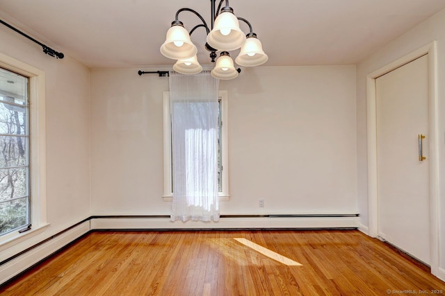 unfurnished dining area with a chandelier, healthy amount of natural light, light wood-style floors, and baseboards