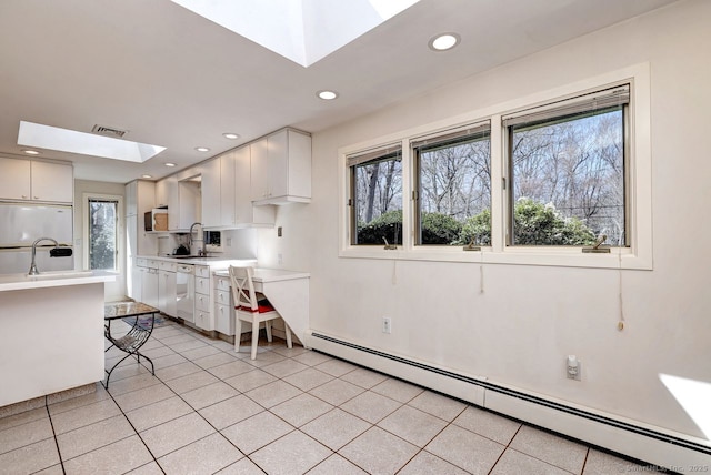 kitchen featuring a skylight, a baseboard heating unit, light countertops, healthy amount of natural light, and recessed lighting